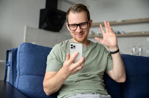Cheerful guy using trendy smartphone for online communication via video meeting Stock Photos