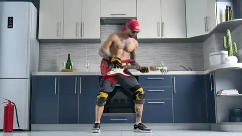 Cheerful guy in work clothes in the kitchen of the apartment fooling around Stock Footage 252892296