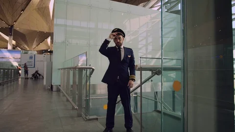 Cheerful handsome bearded man in pilot uniform flipping a cap in the airport Stock Footage 109148499
