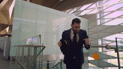 Cheerful handsome bearded man in pilot uniform actively dancing in the airport Stock Footage 109148584