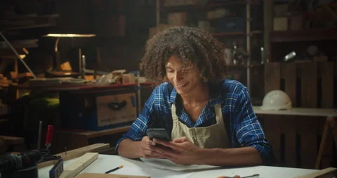 Cheerful handsome curly master carpenter using smartphone smiling chatting Stock Footage 140624666
