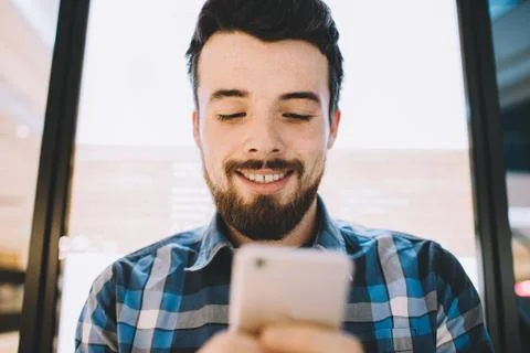 Cheerful handsome young man using his smartphone for chatting with friends Stock Photos