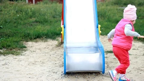 A cheerful happy child rolls down a hill on a playground. Entertainment for Stock Footage 80051412