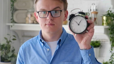 Cheerful hungry man with a clock in the kitchen showing while eating Stock Footage 127685994