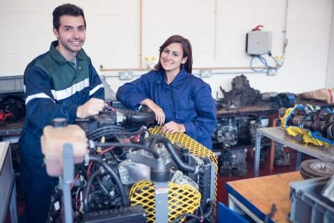Cheerful instructor and trainee standing behind machine Stock Photos