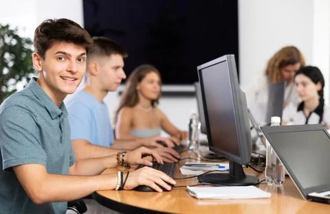 Cheerful interested guy using computer in student library Stock Photos