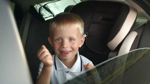Cheerful kid is playing and having fun in the kids car seat during the journey Stock Footage 123623596