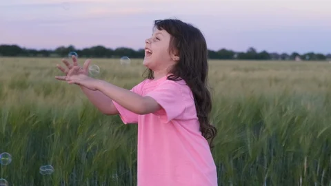 Cheerful kid plays with soap bubbles in a field. Stock Footage 111334218