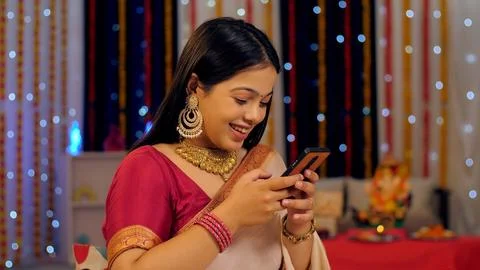 A cheerful lady in a saree using her smartphone during the Diwali festival - ... Stock Photos