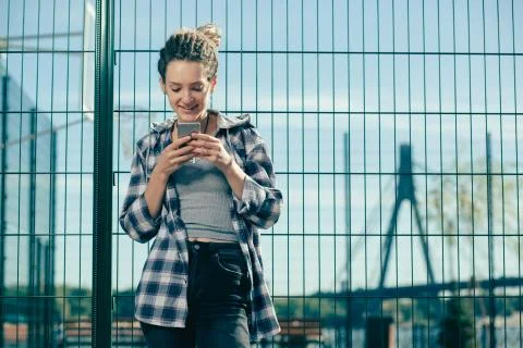Cheerful lady smiling while reading pleasant messages in her smartphone Stock Photos