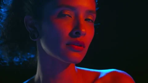 Cheerful latin model in blue-red light strokes skin on black bg Stock-Footage 339399271