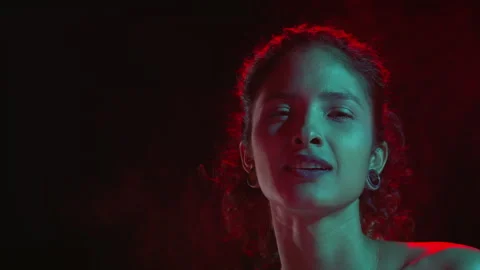 Cheerful latin model in cyan-red light sprays fragrance on black Stock-Footage 341123561