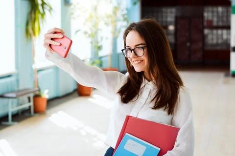 Cheerful learner taking pictures and posting them in social media Stock Photos