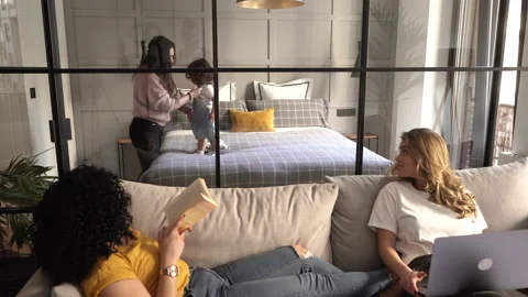 Cheerful Lesbian Couple Lying Down On Sofa Reading and Working While Friend D Stock Footage 153177381