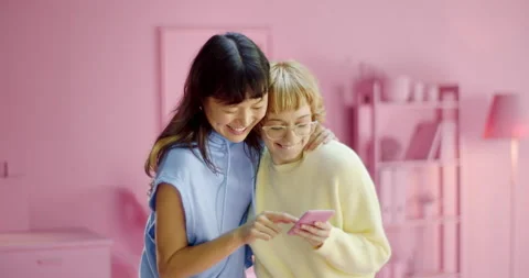 Cheerful lesbian couple using social media application together on a mobile Stock Footage 163647771