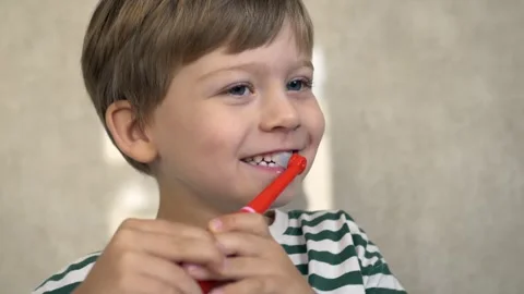 Cheerful little boy brushing teeth with bright electric toothbrush, smiling with Stock Footage 322173114
