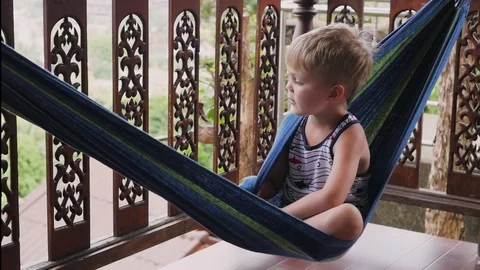 A cheerful little boy is playing while lying in a hammock. Little boy resting on Stock-Footage 125901391