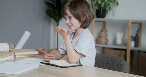 A cheerful little boy is solving math tasks and finding answers to tests to Stock Footage 163250581
