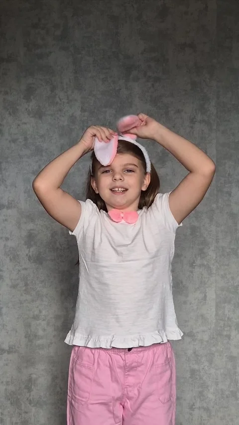 Cheerful little girl with playing with Easter bunny ears on gray background.  Stock Footage 302565797