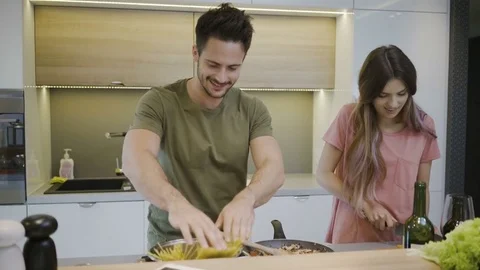 Cheerful loving young couple making pasta together and talking in the kitchen Video stock 79796417