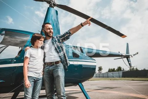 Cheerful male hugging boy on landing field Stock Photos