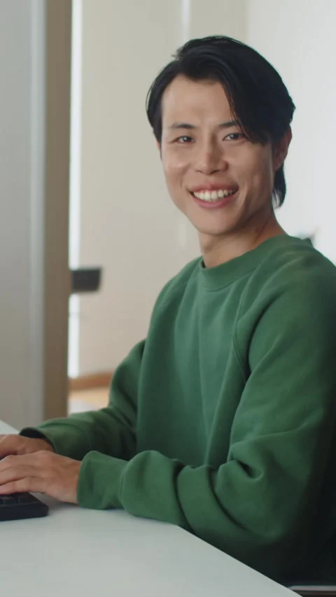 Cheerful Male Programmer Working on Computer and Looking at Camera Stock Footage 256975117