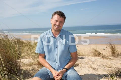 Cheerful man with a blue shirt onthe ocean under blue sky Stock Photos