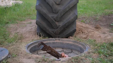 A cheerful man climbs out of the sewer hatch and enjoys freedom and light. Stock Footage 77385038