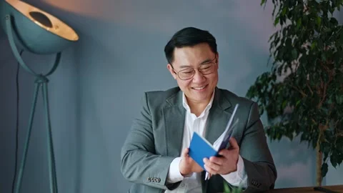 Cheerful man closing laptop while holding printed tickets and documents in hands Stock-Footage 275163320