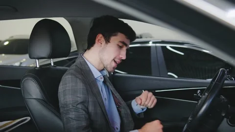 A cheerful man dances in the driver s seat of his brand-new car, enjoying music  Stock Footage 326529157