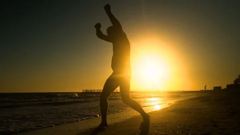 Cheerful man dancing on the beach. He jumps in the sun. The man is having fun Stock Footage 98658241
