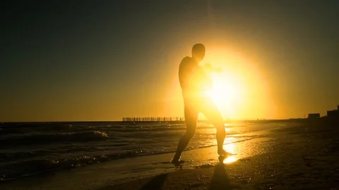 Cheerful man dancing on the beach. He jumps in the sun. The man is having fun Stock Footage 98658302