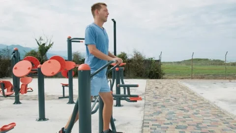 Cheerful man doing cardio workout exercises on elliptical trainer in a street Stock Footage 250560586