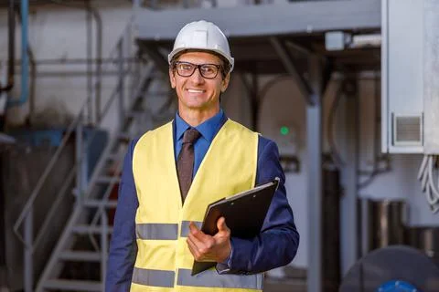 Cheerful man engineer with documents working at factory Stock Photos