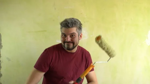 Cheerful man holding a construction roller in his hands 4K Stock Footage 126145572