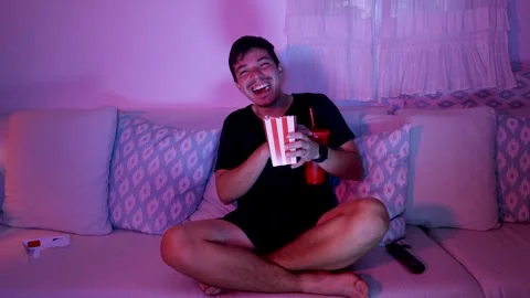 Cheerful man laughing while watching a movie at home Stock Footage 289732472