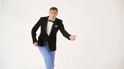 Cheerful man in light-colored pants and black jacket is parodying a guitarist Stock Footage 96202945