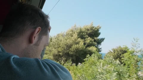 Cheerful man looking out of train window while traveling by railway across the Stock-Footage 269062551