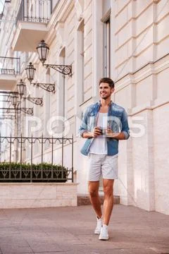 Cheerful man with photo camera walking in the city Stock Photos