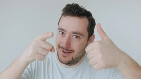 Cheerful man pointing at camera with thumbs-up, expressing confidence and fun. Stock Footage 306259119