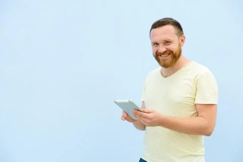 Cheerful man with a red beard points at the tablet, space for text. Stock Photos