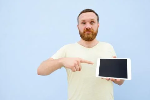 Cheerful man with a red beard points at the tablet, space for text. Stock Photos