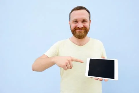 Cheerful man with a red beard points at the tablet, space for text. Stock Photos