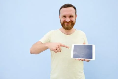 Cheerful man with a red beard points at the tablet, space for text. Stock Photos