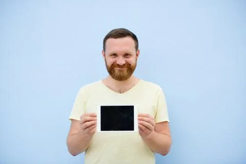 Cheerful man with a red beard points at the tablet, space for text. Stock Photos