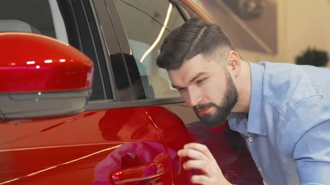 Cheerful man smiling to the camera while examining car at the dealership Stock Footage 147548845