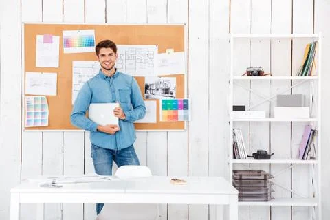 Cheerful man standing at the task board and holding laptop Stock Photos