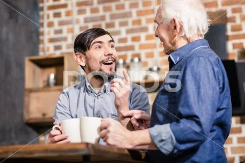 Cheerful man talking with his father in the kitchen Stock Photos