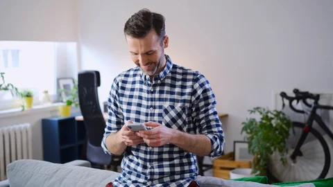 Cheerful man typing message on smarthone from home Stock Footage 126824186