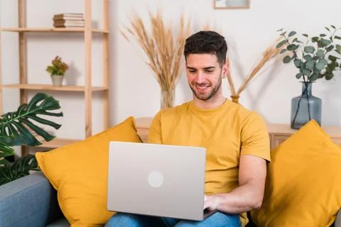 Cheerful man using laptop on sofa Stock Photos
